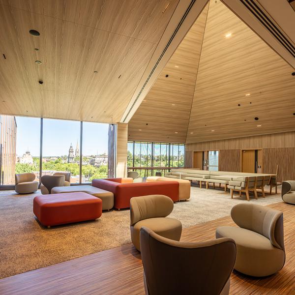 A large room with vaulted timber ceilings and comfortable chairs looks outside to the Bendigo skyline